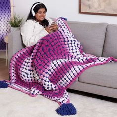 a woman sitting on a couch holding a pink and white blanket