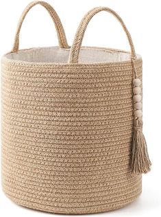 a large woven basket with tassels on the sides and handles, in natural colors