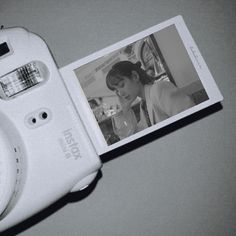 an old camera is laying on the table next to a book with a photo in it