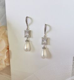 Elegant. Classic. Perfect. Featuring 15mm teardrop shell pearls (natural), this elegant pair of earrings will add glamour to any wedding dress or formal ensemble. All it takes is a simple glance at this unique design to see its extremely classy look that makes an elegant and feminine statement. Shining brightly and quite eye-catching, the shimmer of the pearls is given an extra boost by the clear cubic zirconia that adorn them. Length: 2" (approx. 5cm); Width: 0.4" (approx. 1cm); Weight: 6g. Ava Formal Teardrop Bridal Earrings With Elegant Design, Teardrop Bridal Earrings For Formal Occasions, White Elegant Teardrop Earrings, Elegant Teardrop Cubic Zirconia Bridal Earrings, Silver Teardrop Pendant Earrings For Wedding, Teardrop Pearl White Cubic Zirconia Earrings, Pearl White Teardrop Pearl Earrings With Cubic Zirconia, Pearl White Cubic Zirconia Teardrop Earrings, White Elegant Teardrop Dangle Earrings