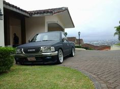 a black car parked in front of a house with a man standing next to it