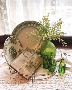 a table topped with plates and vases filled with flowers next to each other on top of a lace covered table cloth