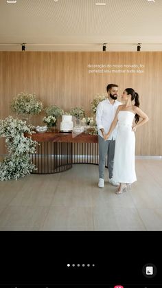 a man and woman standing next to each other in front of a table with flowers