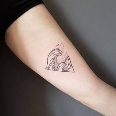 a woman's arm with a tattoo that has a mountain and wave on it