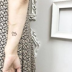 a person with a small cat tattoo on their left arm and hand behind her back