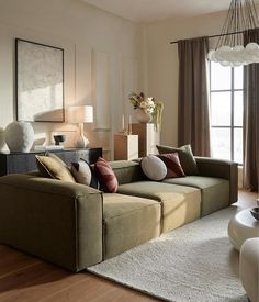 a living room filled with lots of furniture and pillows on top of a wooden floor