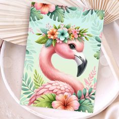 a pink flamingo with flowers and leaves on it's head sitting in front of a fan