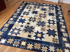 a large blue and white quilt on the ground in a room with wooden floors,