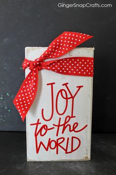 a red and white sign that says joy to the world on it with a bow