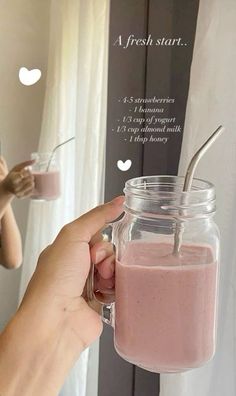 a person holding a glass jar with a smoothie in it