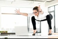 a woman in black pants and white shirt doing a trick on a laptop