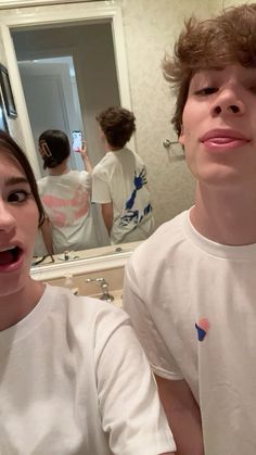 a young man and woman standing in front of a bathroom mirror with their mouths open