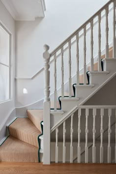 a white stair case next to a window in a house