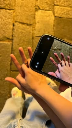 a woman holding up her cell phone to take a selfie with her hand and fingers