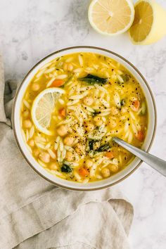 a bowl of pasta soup with lemons and garnishes on the side