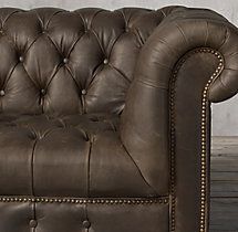 a brown leather couch sitting on top of a wooden floor