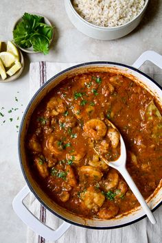 a large pot filled with shrimp and rice next to a bowl full of other food