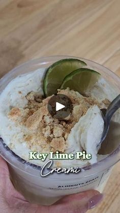 a person is holding a bowl of ice cream with limes and coconut on top