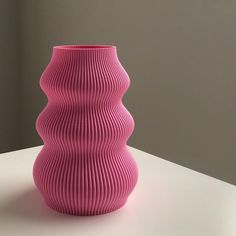 a pink vase sitting on top of a white table