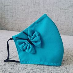 a blue cloth bag with a large bow on the front, sitting on a couch