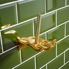 a gold hand on the side of a green tiled wall