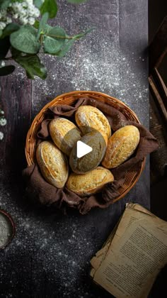 a basket full of bread sitting on top of a table next to an open book