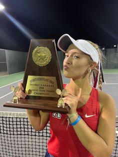 a female tennis player holding up her trophy