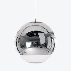 a mirror ball hanging from the ceiling in front of a white wall with people standing around it