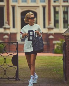 a woman walking down a sidewalk carrying a purse