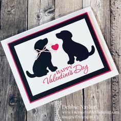 a valentine's day card with two dogs and a heart on the front, sitting on a wooden surface