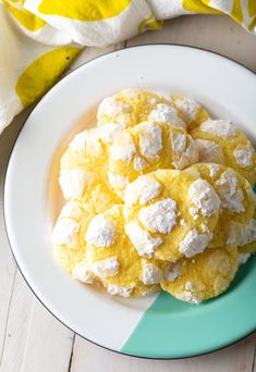 a plate full of lemon meringue cookies with powdered sugar on top, next to a yellow and white towel