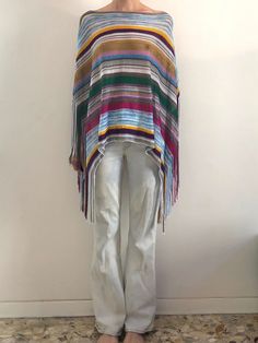 I looove Missoni!  Super cool Y2K striped rayon Missoni fringe poncho top.  Such a good boho vibe. This is a summer poncho that's gonna be great after the beach.  Can be worn two different ways - turn it and twist it for different effects.  Knit is made from rayon and is light and feels slinky.  Striped pattern with bright colors and metallic threads.  Sheer.  Can be worn as a stand alone top or poncho over whatever you like.  Fringe at the edges. Label Missoni, 97% rayon, 3% poly, Dry clean only.  Good vintage condition, please be careful with the knit as it is delicate.  Measurements  Shoulder to sleeve - 35cm/ 14inches Shoulder to hem 62cm/ 24inches Fringe 22cm/ 9inches Models Measurements Shoulders 42cm/ 16.5inches Chest 84cm/ 33inches Waist 66cm/ 26inches Hips 92cm/ 36inches Height 17 Hippie Style Fringe Poncho For Spring, Beach Poncho With Multicolor Fringe, Beach Poncho With Fringe In Multicolor, Multicolor Fringe Poncho For The Beach, Multicolor Fringe Poncho For Beach, Beach Multicolor Poncho With Fringe, Spring Multicolor Fringe Poncho, Summer Poncho, Beach Poncho