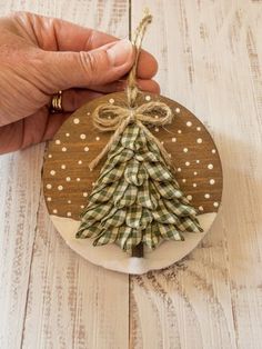 A 4" round wood ornament displaying a snowy scene with a ribbon pine tree. The wood is first stained (front and back) and then the falling snow and snowy hill background is painted on the front before the wood is sealed with a varnish. The tree is made using green and ivory plaid ribbon with layers of felt underneath to create the 3D effect. A jute bow accents the top of the tree. The tree trunk is a piece of a wooden dowel that is painted brown. Snowy Woods, Farmhouse Christmas Ornaments, Winter Wood, Wooden Ornament, Holiday Crafts Christmas, Farmhouse Christmas Decor, Christmas Ornament Crafts, Christmas Crafts Decorations, Ornament Crafts