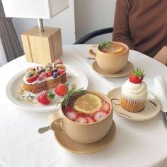 three desserts are sitting on small plates on a white tablecloth with a man in the background