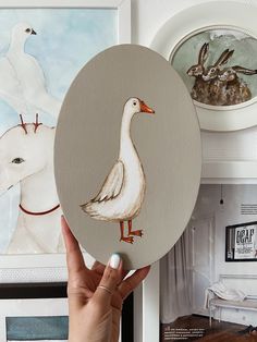 a person holding up a painting with a duck on it