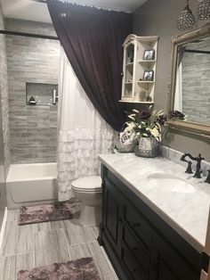 a bathroom with a toilet, sink and bathtub next to a shower curtain that has flowers on it