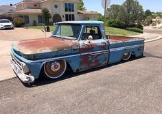 an old blue truck parked in front of a house