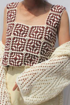 a close up of a person wearing a knitted sweater and holding a crochet shawl