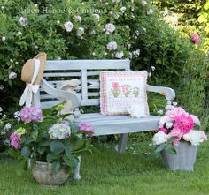 a wooden bench sitting in the grass next to flowers