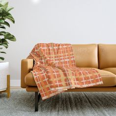 a couch with a blanket on it next to a potted plant