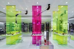 the interior of a retail store with neon colored glass walls and shelves filled with bottles