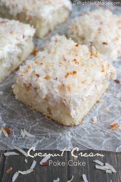 coconut cream poke cake is cut into squares and placed on a piece of wax paper