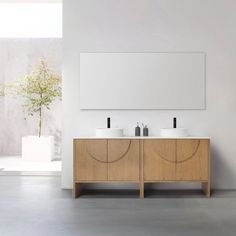 two white sinks sitting next to each other on top of a wooden cabinet under a mirror