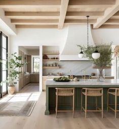 an open kitchen and dining area with wooden beams on the ceiling, hardwood flooring, and green cabinetry