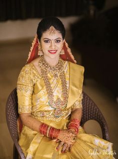 a woman sitting in a chair wearing a yellow and red outfit with jewelry on her head