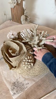 a woman is working on an arrangement of flowers in her home studio, using clay to create them