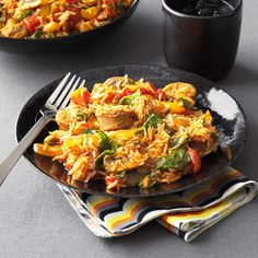 two plates of food on a table with silverware and cups in the background,