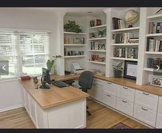 a home office with white bookcases and wooden desk in front of the window