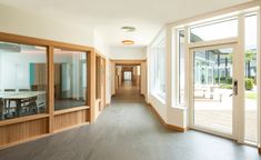 an empty room with large glass doors and wooden furniture on either side of the hallway