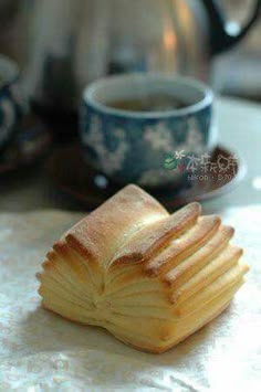 a stack of bread sitting on top of a table next to a cup of coffee